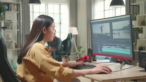 Asiatische Videoredakteurin arbeitet mit Filmmaterial und Ton auf ihrem PC im Büro