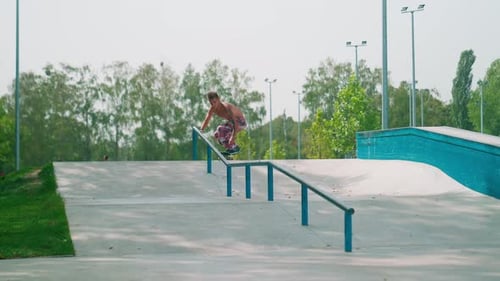 Shirtless Skateboarder Grinds Rail at Skate Park