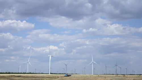 Wind Turbines Spinning in Rural Field, Sunny Day