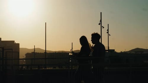 Silhouetted Couple Walking on Balcony at Sunset