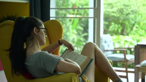 A girl sitting on the sofa and reading a book in cozy home