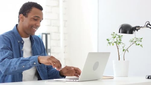 Afro-American Man Coming to Office, Starts Work on Laptop