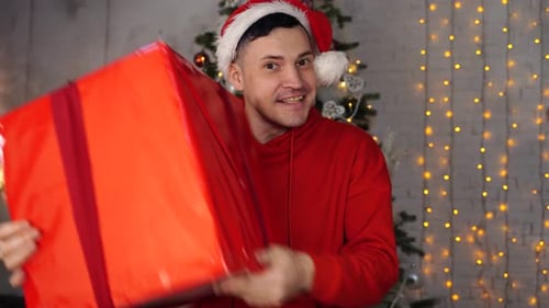 Man in Santa Hat Holding Christmas Gift