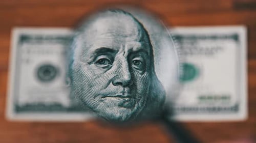 Examining One Hundred Dollar Bill with Magnifying Glass