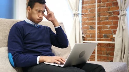 Worried Young Adult Typing on Laptop Indoors