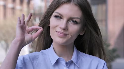 Smiling Woman Makes Ok Gesture Outdoors