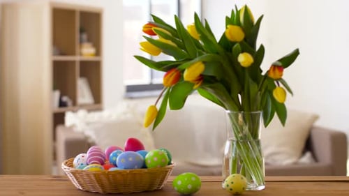 Farbige Ostereier im Korb und Blumen zu Hause