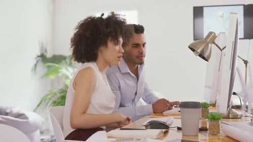 Two colleagues working on computer in creative office