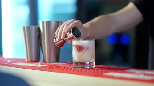 Expert Bartender Pours Cocktail Ingredient into Glass