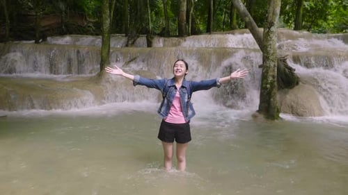 Woman Enjoying Waterfall in Lush Tropical Forest