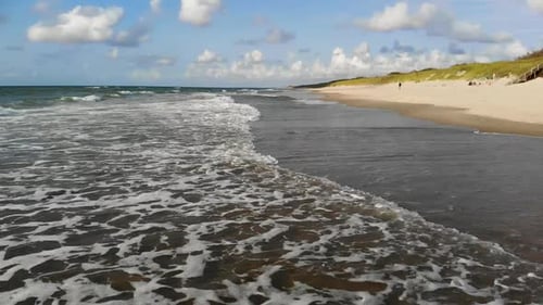 LUFTAUFNAHME: Standbild einer Welle, die an der sandigen Küste zusammenbricht