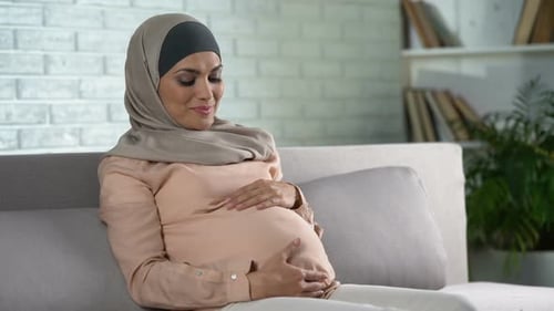 Pregnant Woman Smiling and Touching Abdomen