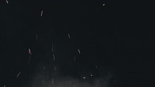 Lagerfeuerfunken erheben sich vor schwarzem Hintergrund. Zeitlupe