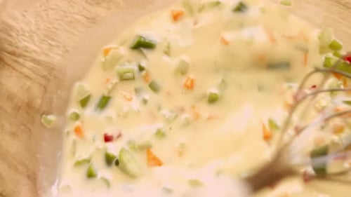 Chopped Vegetables Being Stirred into Eggs