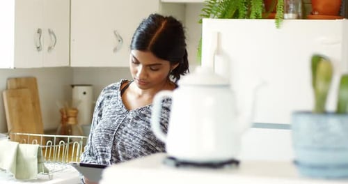 Frau benutzt digitales Tablet in der Küche