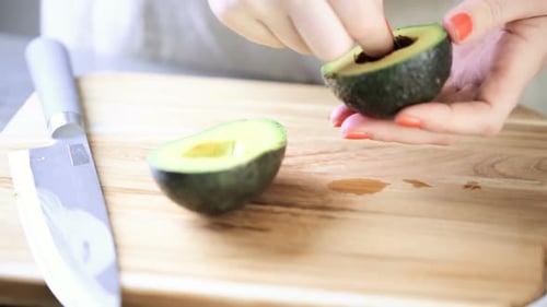 Woman Prepares Avocado on Cutting Board