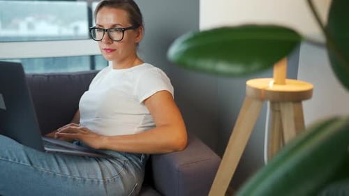 Woman Works on Laptop Relaxing on Couch