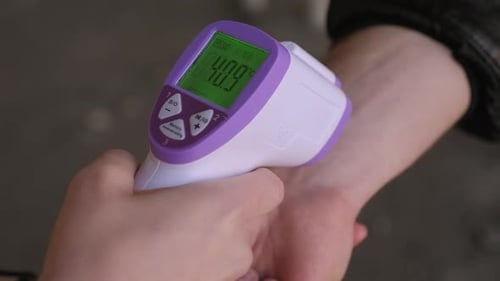 A Doctor Measuring a Man's Temperature on His Arm Using a Digital Thermometer