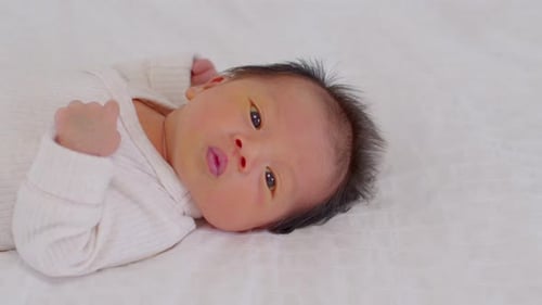Top view happy newborn baby lying sleeps on a white blanket comfortable