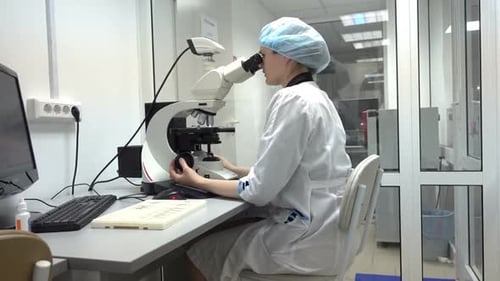 Female Scientist Uses Microscope in Bright Laboratory