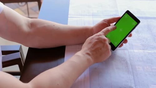Construction engineer using a smartphone with a green screen looking for information on the internet