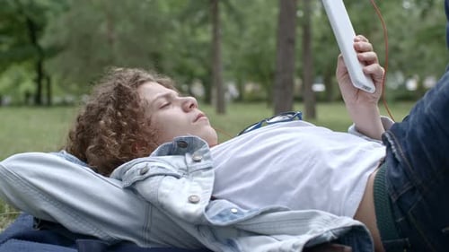 Boy Watching Video on Tablet while Resting in Park