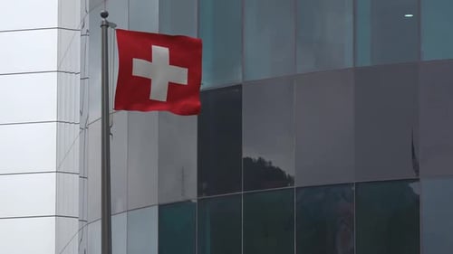 Swiss Flag Waving on Modern Building Facade
