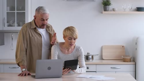 Couple Calculating Finances Together in Bright Home Kitchen