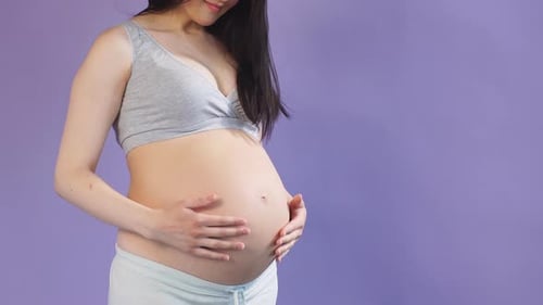 Loving Pregnant Woman Holding Her Belly While Posing in Studio