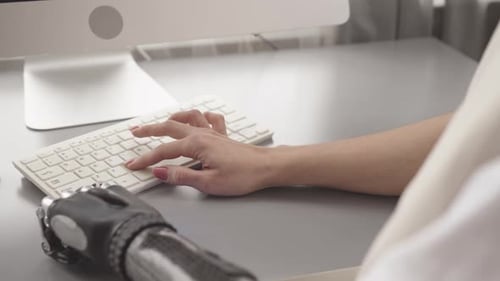 Frau mit Armprothese schreibt Programmcode auf dem Computer