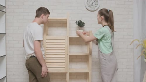 Couple heureux, femme et homme, se réjouissent de la réussite de l'assemblage de la bibliothèque en bois