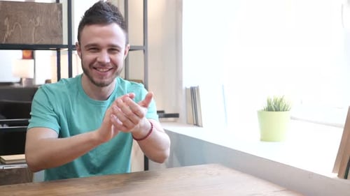 Young Adult Clapping Hands at Wooden Table