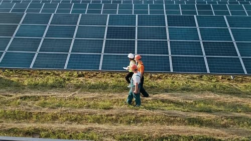 Three Employees of Alternative Power Plant Walking and Talking About Scheme of