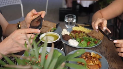 Two Women Photographing Delicious Brunch with Mobile Phones