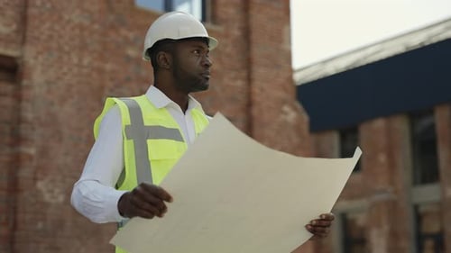 Vorarbeiter mit Helm analysiert Baupläne auf der Baustelle
