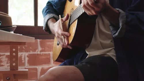 asian male Musician Guitar man in studio with man’s hand composing music while playing guitar.