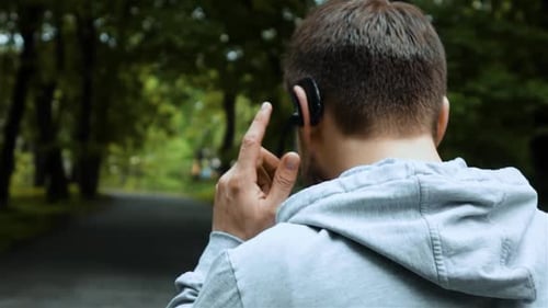 Road Runner Talking By Phone with Bluetooth Headset in Autumn Park