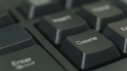 Finger wiederholt die Entf-Taste auf einer schwarzen Tastatur drücken.