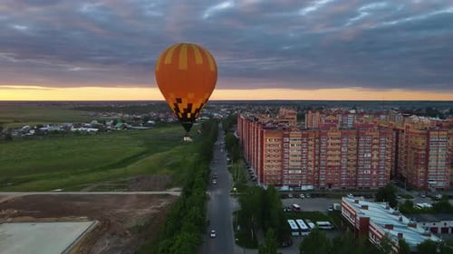 Hot Air Balloon Flies Over Town at Sunset