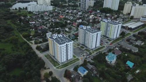 City block. Modern multi-storey buildings among cottages. Flying at dusk at sunset.