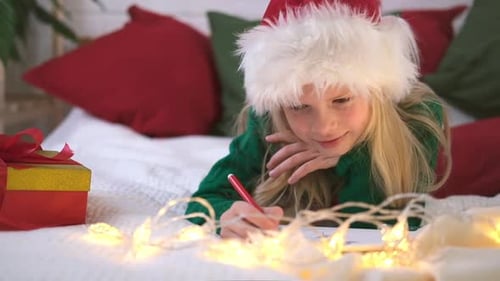 Girl Writing Christmas Letter on Bed with Lights