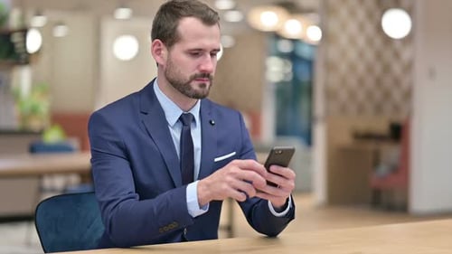 Serious Businessman Using Smartphone in Office