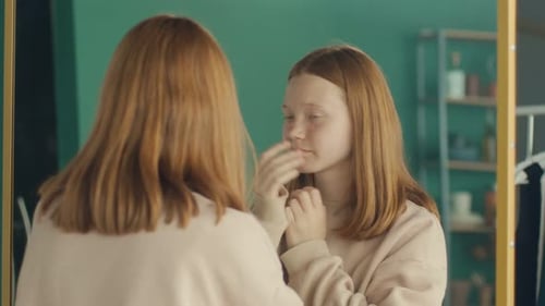 Ein rothaariges Teenager-Mädchen untersucht ihr Spiegelbild
