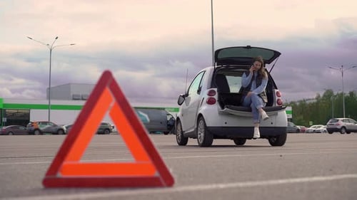 Woman talking on phone at broken down car
