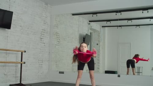 Young Woman Exercising with Band in Workout Studio