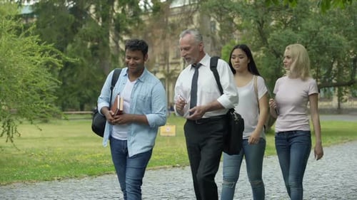 Students and Teacher Walking in Park Near College, Discussing Science Project