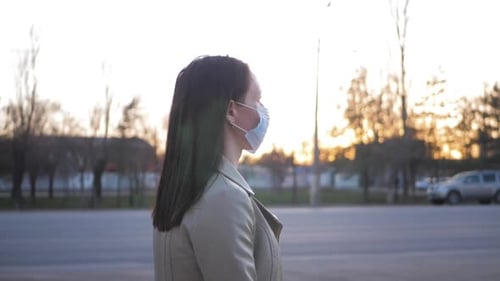 Young Woman in a Medical Mask for Protection From the Epidemic on the Street in the City. Concept of