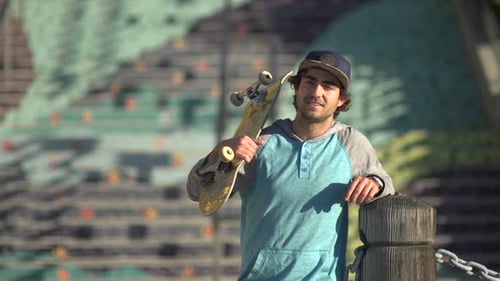 Young Man with Skateboard Smiling in Urban Setting