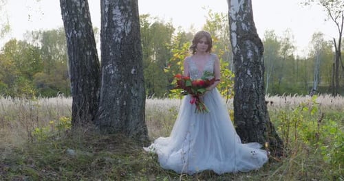 Woman with Bouquet in Wedding Gown in Nature
