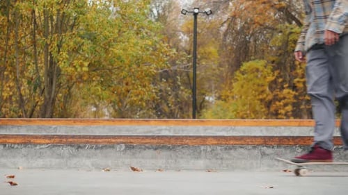 Skater Practicing in the Autumn Concrete Skate Park Making Tricks and Rides in Ramp
